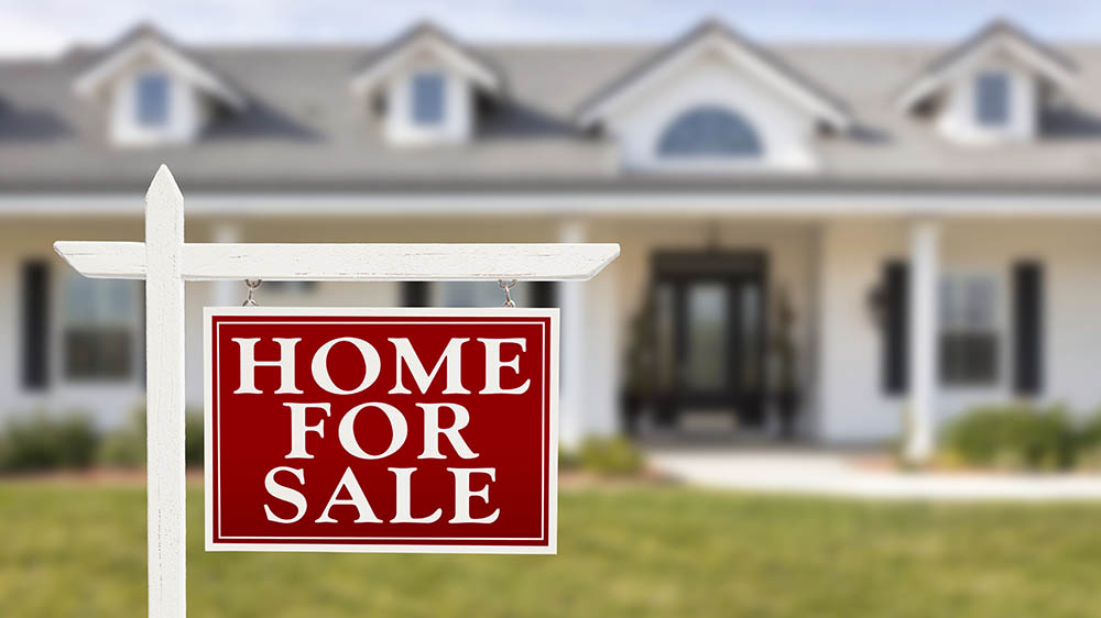 For sale real estate sign in front of a house before home inspection services are scheduled
